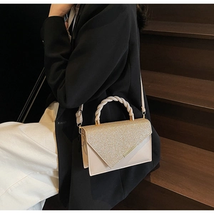 Détail d'un sac à main pailleté or champagne avec poignée tressée sur un mannequin