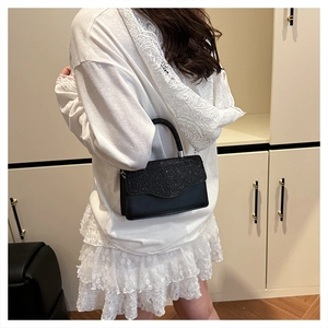 Detail of a chic black crossbody bag with sequined flap and scalloped edge for women