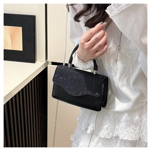 Close-up of elegant black sequined crossbody bag with silver round handle and chain strap
