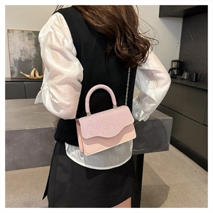 Pink sequin crossbody bag shown on model featuring silver chain strap and stylish top handle