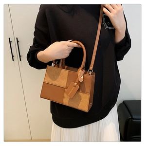Détail d'un sac à main carré bicolore en cuir marron et daim kaki avec bandoulière