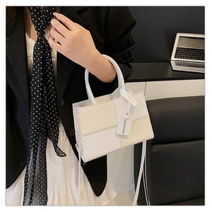 Detail of color-block tote bag featuring white leather tag and slim shoulder strap