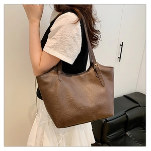 Detail of dark brown vintage leather tote bag with soft texture and long straps