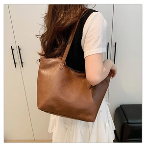 Brown soft leather tote bag detail showing large capacity and vintage texture on model