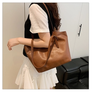Detail of dark brown tote bag with vintage lychee texture carried by a model