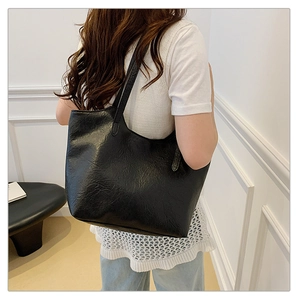 Close-up of black retro soft leather tote bag with pleated texture worn on the shoulder