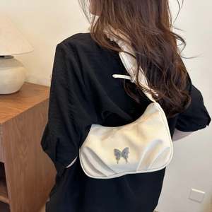 Beige pleated shoulder bag with silver butterfly pendant and ruffled strap detail
