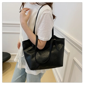 Detail shot of black textured leather tote bag with slim shoulder straps on model