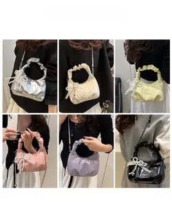 Detail einer glänzenden Faltenhandtasche mit Perlenspitzen-Schleife und Kettenriemen