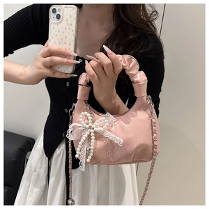 Nahaufnahme der rosa Handtasche mit Faltenhenkel, Perlenspitzenbogen und Metallkette