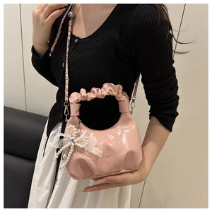 Detail der rosa glänzenden Handtasche mit Falten Griff, Perlenbogen und Kette