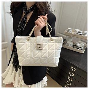 Close-up of white quilted tote bag featuring gold geometric clasp and chain strap detail