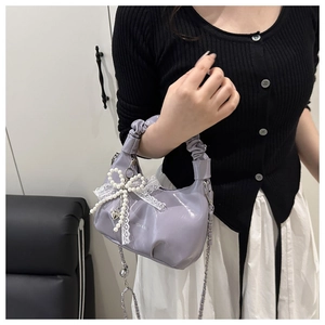 Detail der lila gefalteten Cloud-Bag mit glänzendem Lack, Spitzenschleife und Perlen