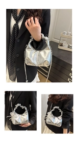 Details der silbernen Metallic-Faltenhandtasche mit gerafftem Griff und Kettenriemen