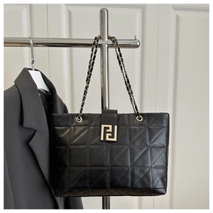 Detail of black quilted tote bag featuring geometric patterns and metal chain strap