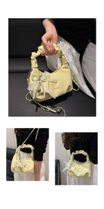 Detail der gelben glänzenden Handtasche mit Faltenverschluss, Perlenbogen und Metallkette