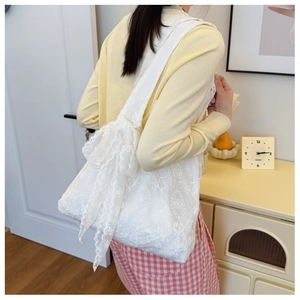 Close-up of intricate floral lace embroidery and a decorative bow on the white tote bag