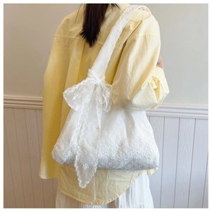Close-up of white floral embroidery lace texture and elegant bow on tote bag