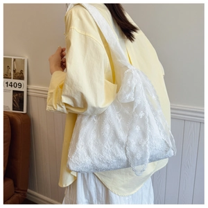 Detail of delicate white floral lace embroidery on a high-capacity shoulder tote bag