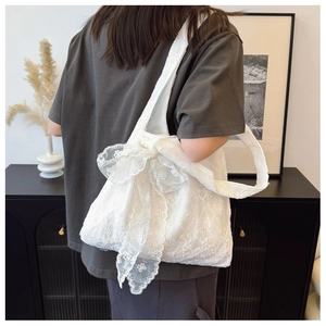 White lace tote bag with large bow and embroidery shown in a minimalist home setting