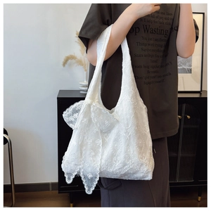 Detail of delicate white lace embroidery and large ribbon bow on a shoulder tote bag