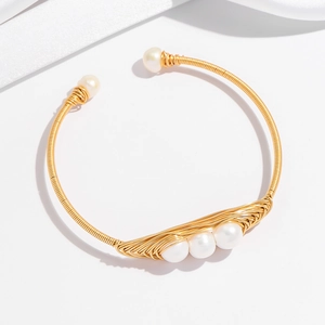Détail d'un bracelet en fil doré orné de cinq perles blanches sur de la soie élégante