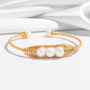 Détail d'un bracelet artisanal en fil doré torsadé avec perles d'eau douce naturelles