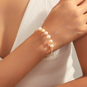 Eleganter offener Goldarmreif mit sieben runden Naturperlen für einen minimalistischen Look