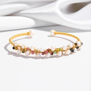 Detail of handcrafted gold wire bracelet featuring natural pearls and colorful gemstones