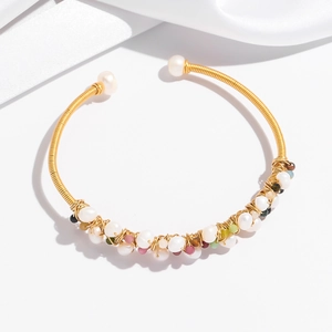 Detail of handmade wire-wrapped gold bracelet with white pearls and colorful gemstones