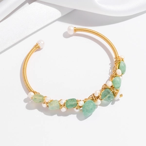 Macro detail of handmade gold wire-wrapped bangle with green stones and pearls