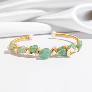 Close-up of golden wire-wrapped bangle with green quartz stones and small pearls