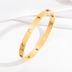 Polished gold stainless steel bangle with cutout star patterns on white silk background