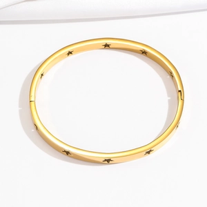 Detail of gold stainless steel bangle showing hollow star patterns and polished finish