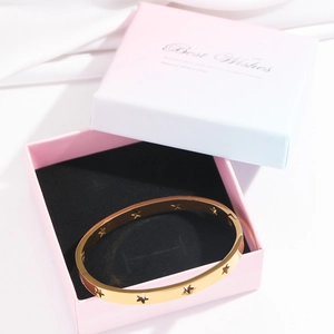Detailed view of gold star hollowed bangle presented in a premium gradient gift box