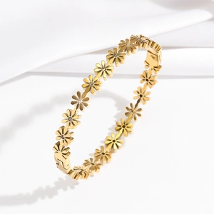 Elegant gold daisy flower bangle bracelet with shimmering crystals on a white silk background