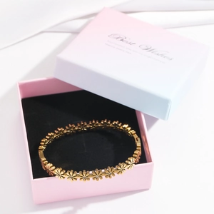 Detailed shot of golden daisy flower bracelet with crystals in a pink gift box