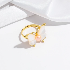 Detailed macro view of a golden butterfly ring with shell inlay and pink pearl center