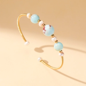 Elegant gold-plated open bangle with natural pearls and blue stones in a minimalist design