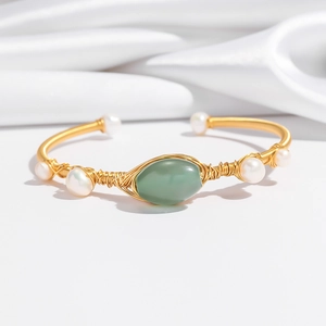 Detailed shot of handmade gold wire-wrapped bracelet with green gemstone and pearls