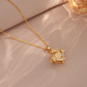 Close-up of golden flower pendant necklace with opal center and zircon details