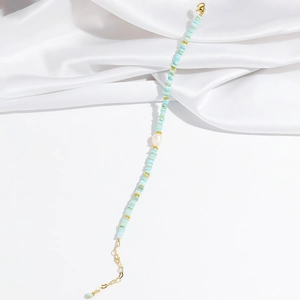 Détail de perles en pierre bleu clair et perle blanche sur bracelet doré chic