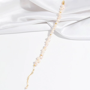 Gros plan du bracelet de perles baroques avec billes dorées et fond en soie