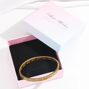 Detailed macro of gold vintage Greek meander pattern bangle inside a premium gift box