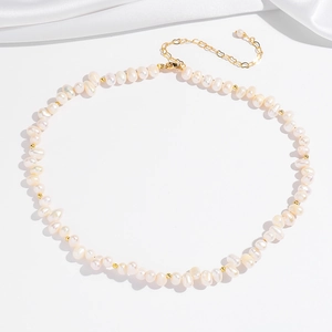 Détail du collier de perles baroques avec perles dorées sur fond de soie blanche