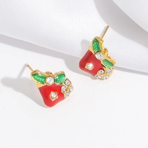 Detailed close-up of festive red bell earrings with green leaves and shiny rhinestones