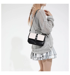 Side view of model carrying a black and white minimalist leather crossbody bag with chain handle