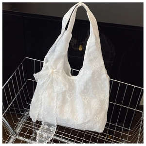 Close-up of white floral embroidery and delicate lace bow on the vintage mesh tote bag
