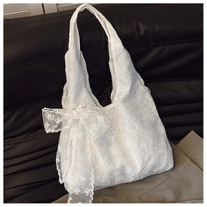 Detailed view of white floral lace embroidery and large ribbon bow on a tote bag