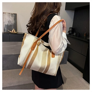 Detailed side view of large vertical striped canvas tote bag with brown leather straps